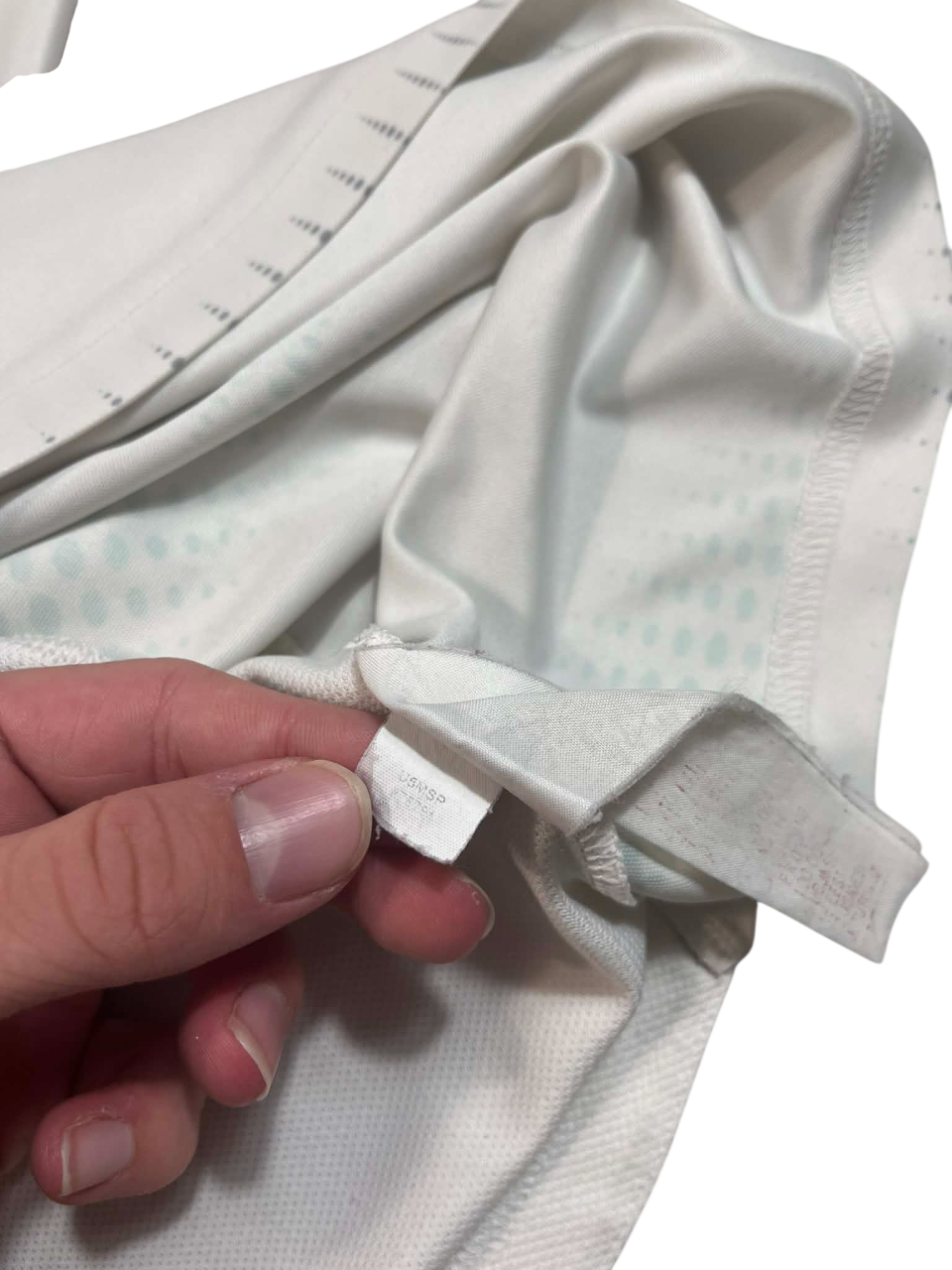 Fehér streetwear póló címkéje közelről, kézben tartva, vintage stílus