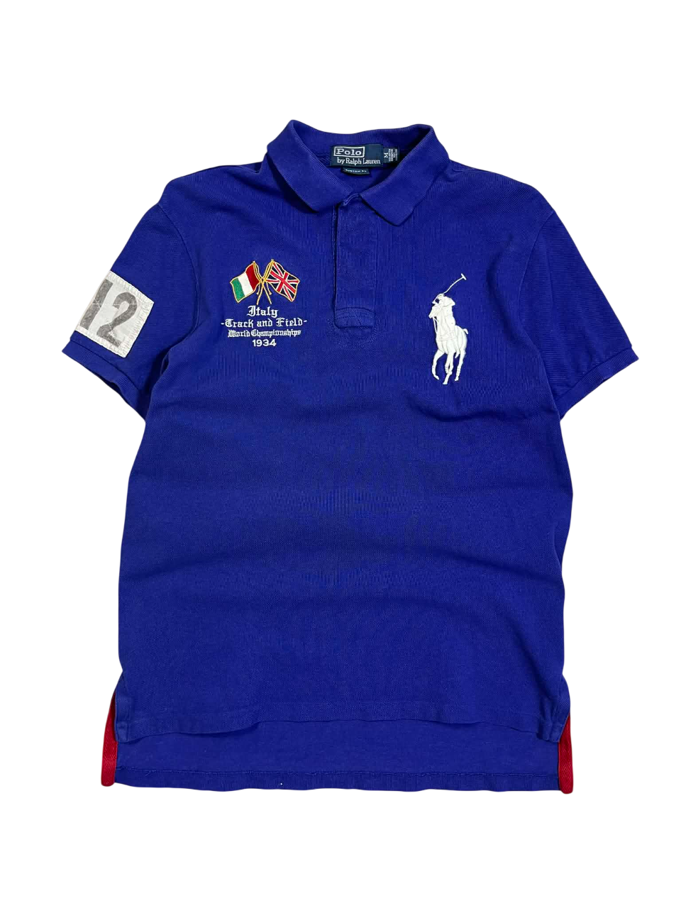 Kék vintage póló gallérral, mellrészén felvarrott zászlók, sportos divat, hímzett logóval.