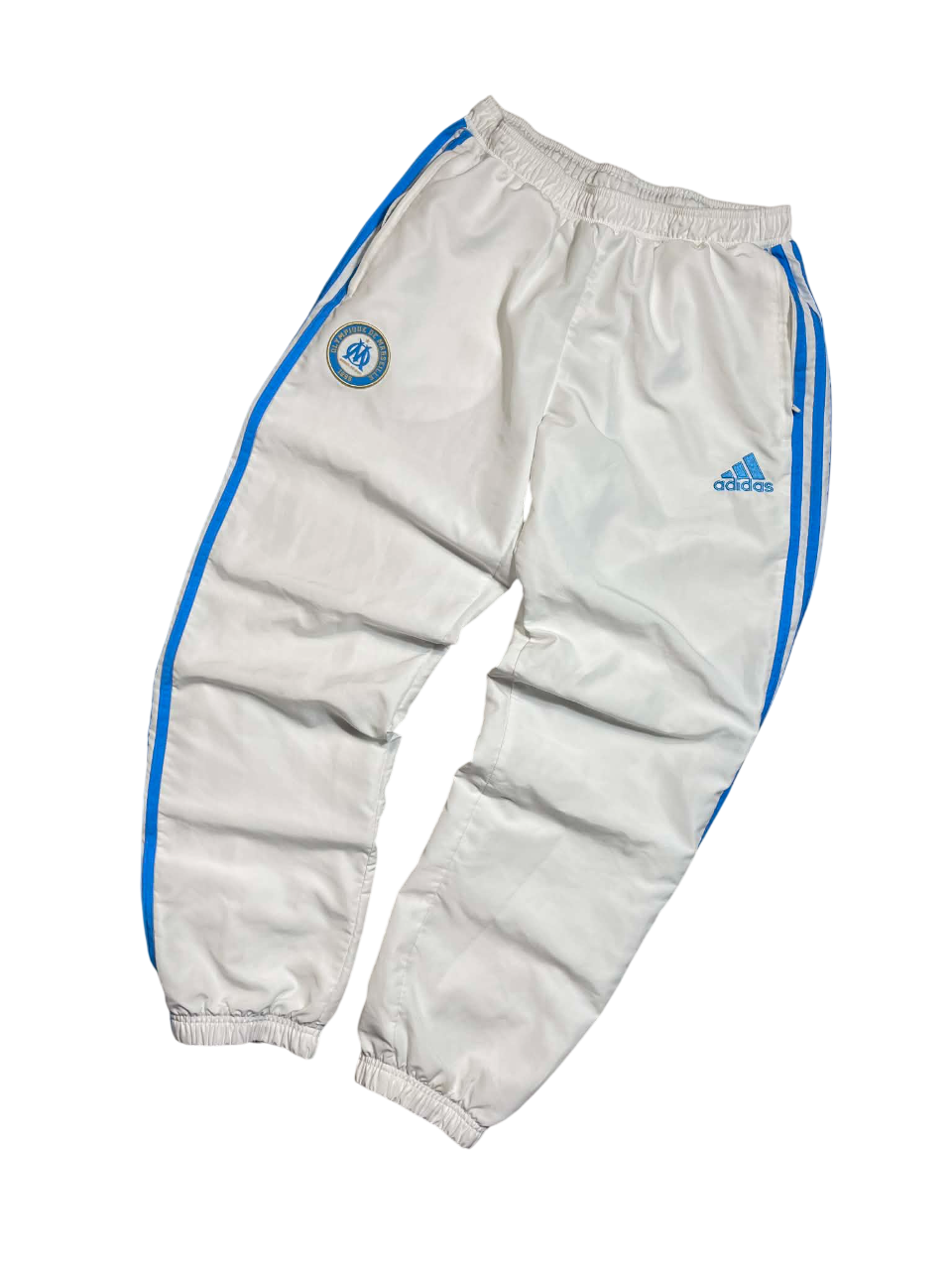 Fehér vintage Adidas melegítőnadrág, kék csíkkal és hímzett logóval, streetwear stílusban