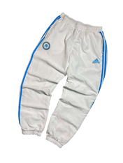 Fehér vintage Adidas melegítőnadrág, kék csíkkal és hímzett logóval, streetwear stílusban