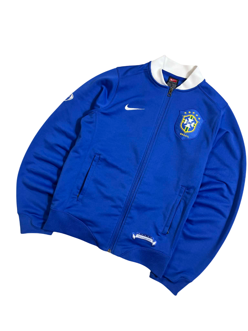 Kék vintage Nike Brasil cipzáros streetwear dzseki, fehér gallérral és hímzett címerrel.