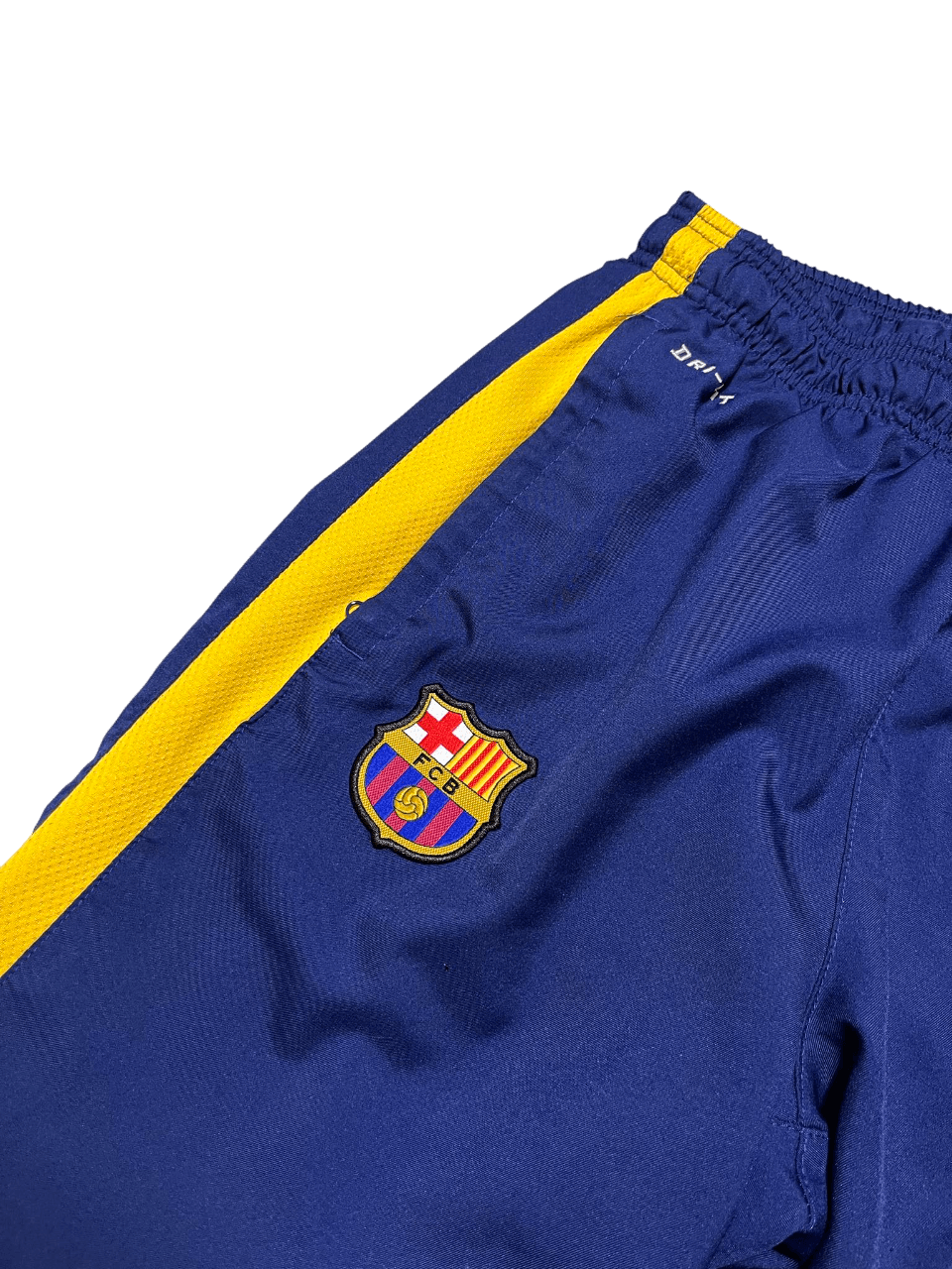 Kék és sárga, gumis derekú focimelegítőn Barcelona címer, sportos streetwear stílus.