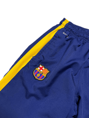 Kék és sárga, gumis derekú focimelegítőn Barcelona címer, sportos streetwear stílus.